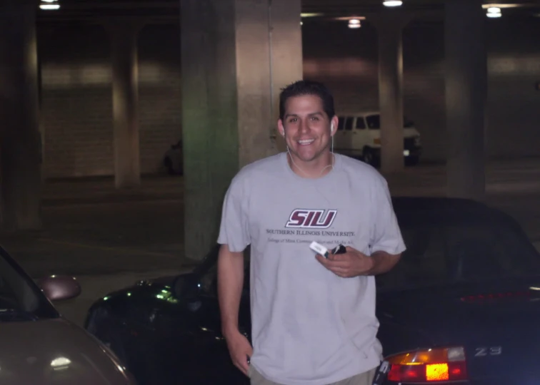 a guy standing outside in a parking garage with a game control