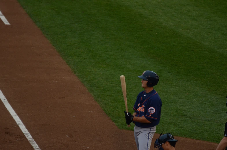 a man in uniform holds a baseball bat while a player holds his glove