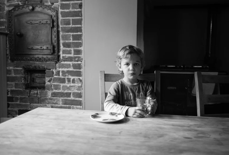 a small boy at a table with a plate and drink