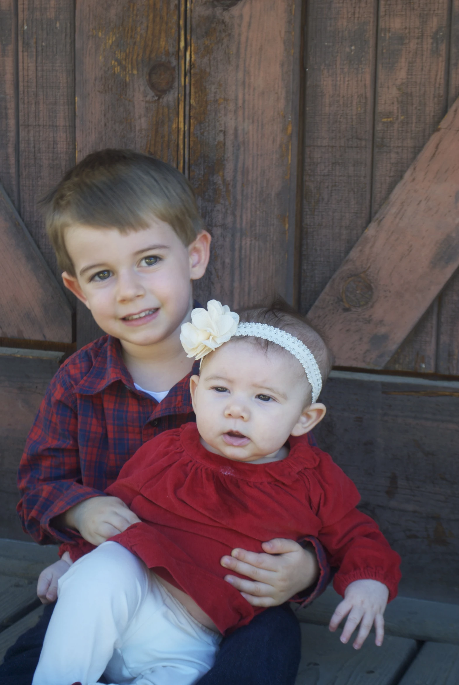 two s sitting down in front of a wooden door