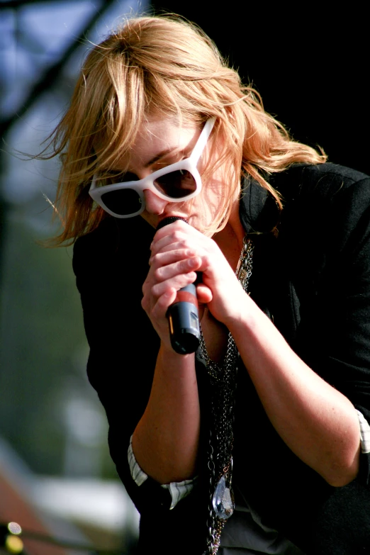 a woman with glasses on a stage singing