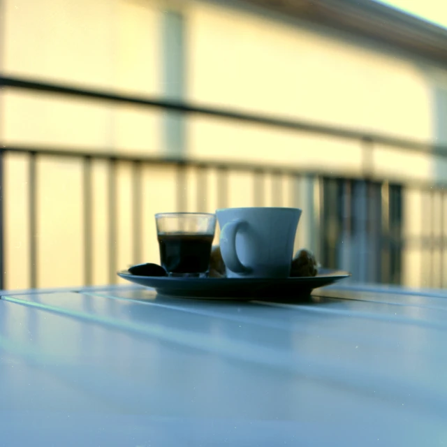 two cups of coffee sit on a plate outside