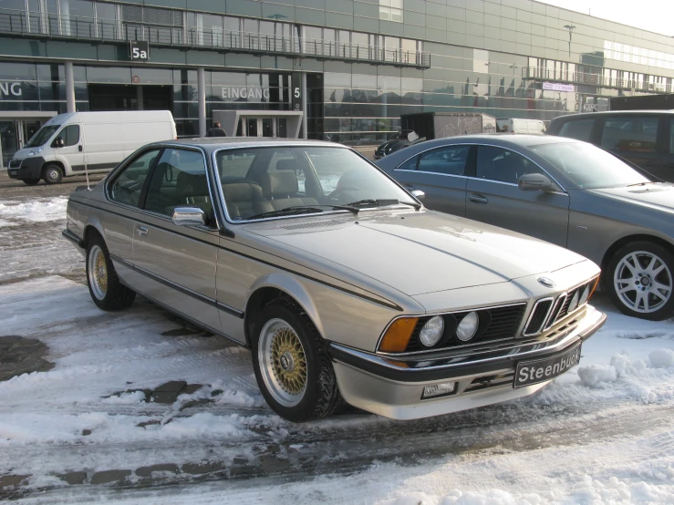 two cars parked in front of a large building in the snow