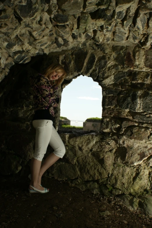 a young woman is standing in the stone tunnel