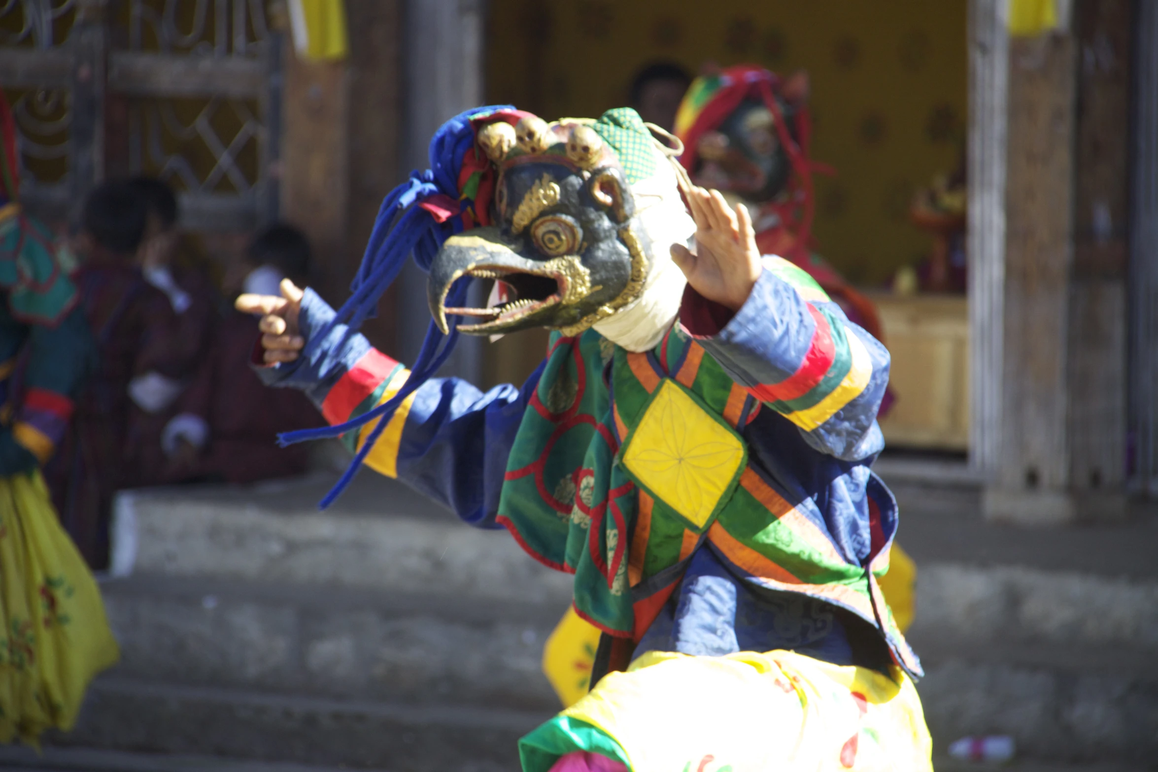 an elaborately painted clown poses with his hands in the air