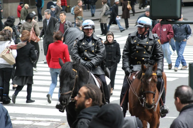 two mounted police officers riding on horses down the street