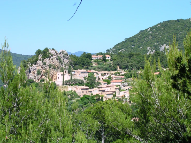a village nestled between trees in front of a mountain