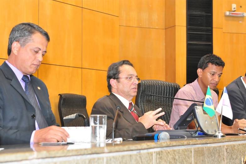 two men sitting at a table as others talk