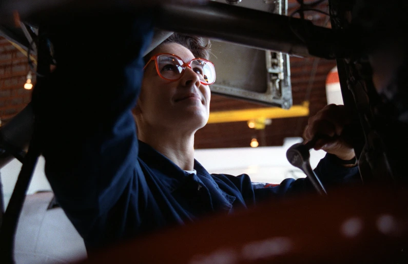 a man in glasses is holding onto the rim of a car