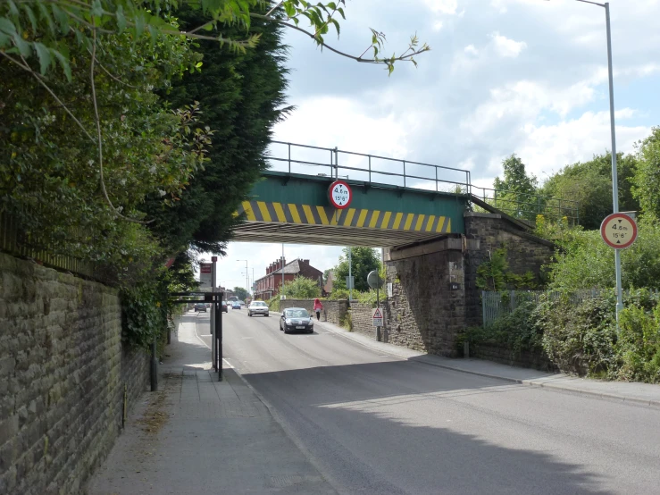 a road under a bridge next to a wall and traffic signal