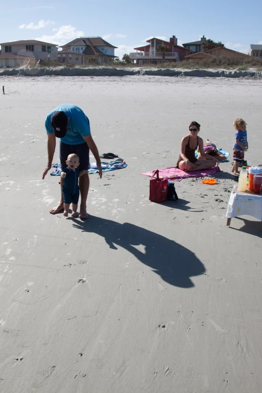 a man in blue shirt and woman on beach with small child