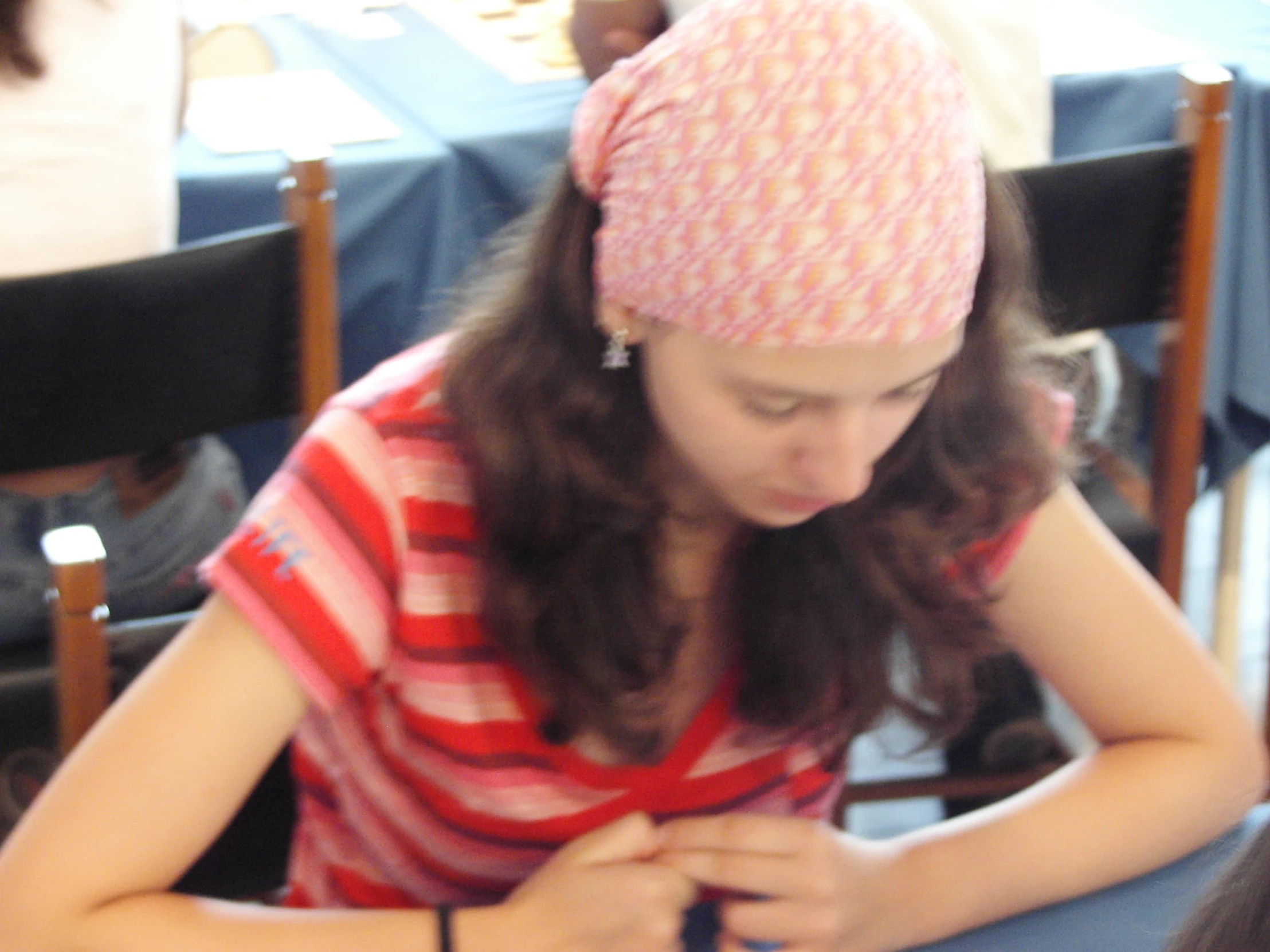 a girl sits at a table in front of two empty chairs