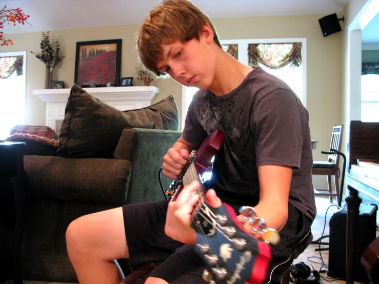 a young man is playing with an electric guitar