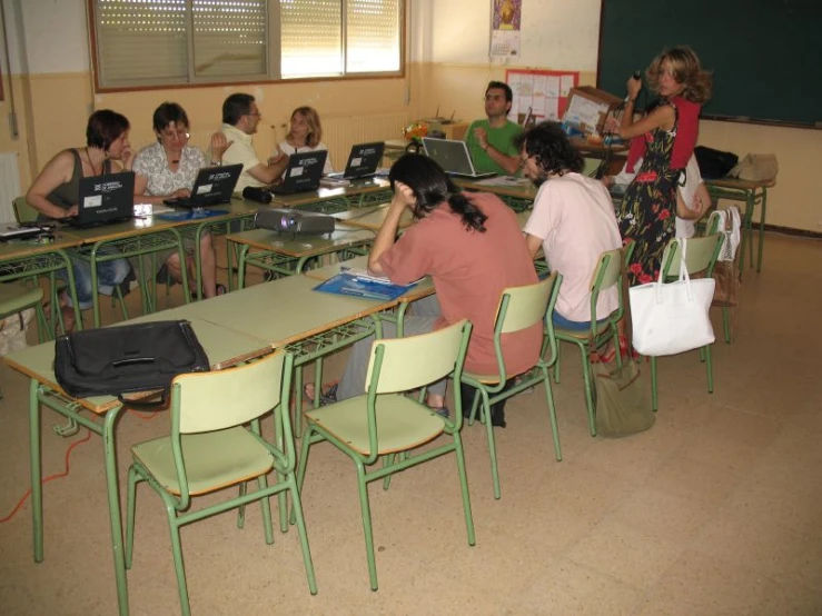 a group of students sitting in a classroom using laptops