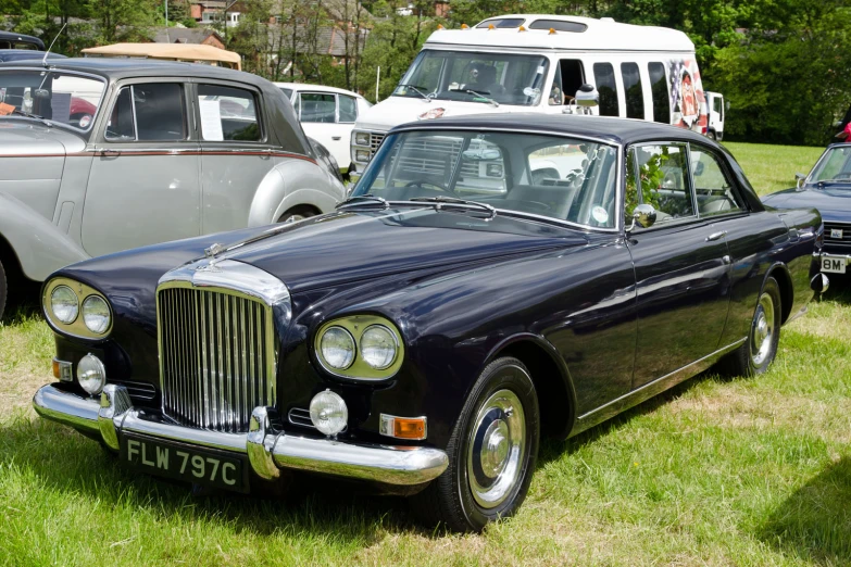 a blue vintage car parked next to two other cars