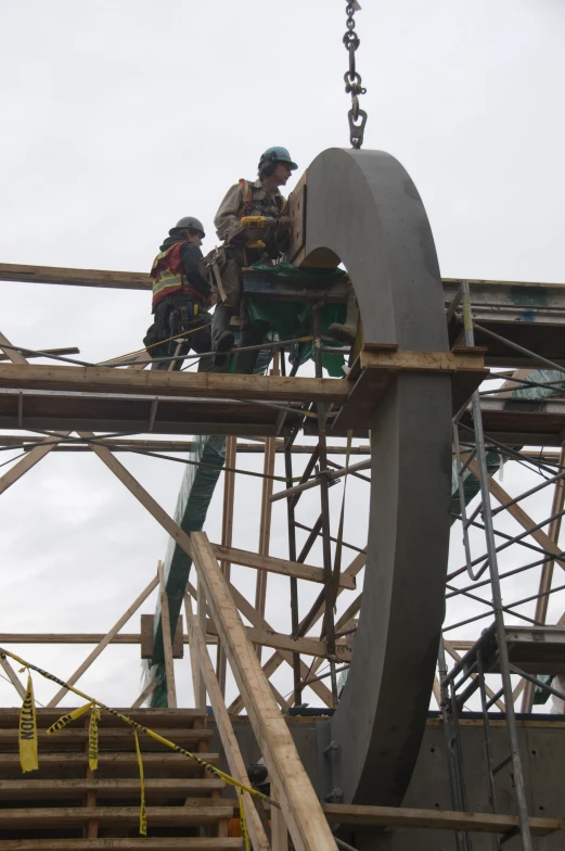 two construction workers on a hoist installing a structure