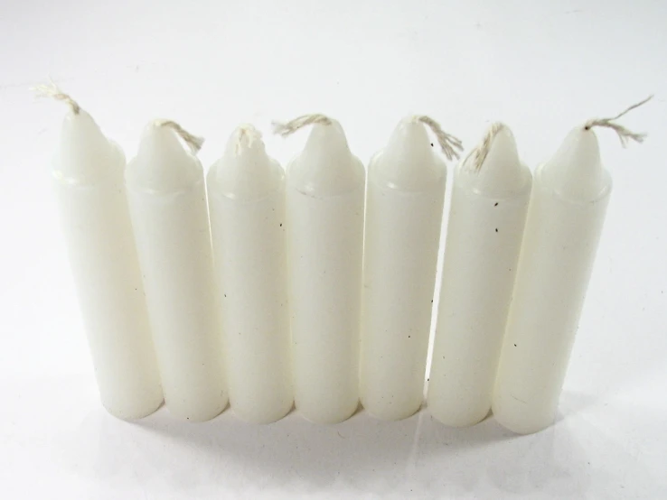 a row of five white candles with string tied around it