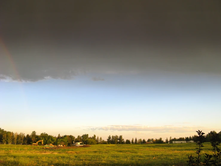 a field with a rainbow coming out of the sky