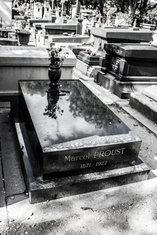 a granite grave in the middle of cemetery next to other headstones