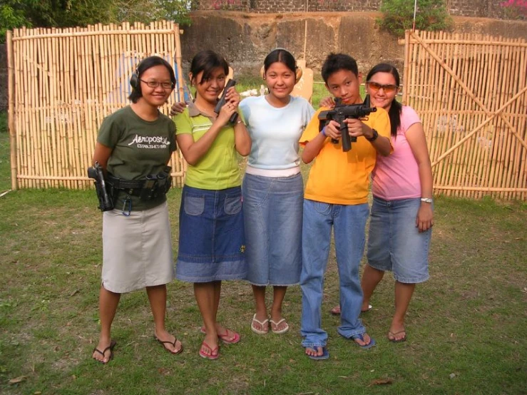 four girls pose for the camera in front of a bamboo fence