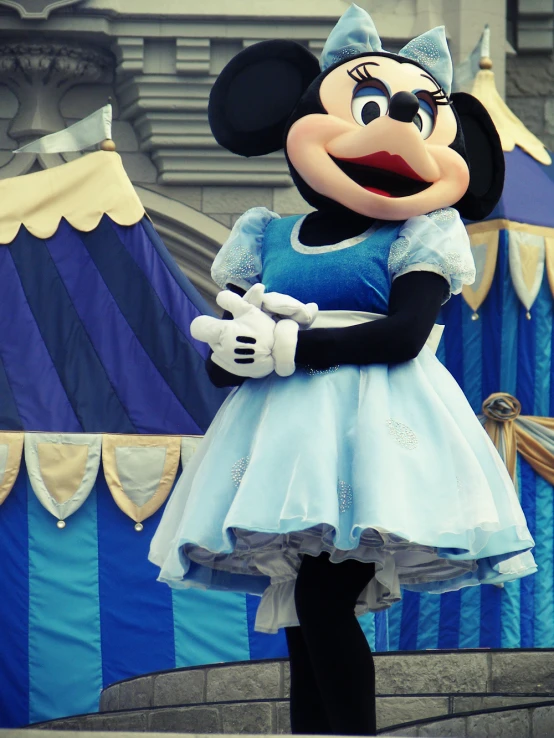 a woman dressed up as mickey mouse in front of a blue and yellow castle