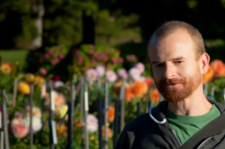 the bearded man is standing next to some flowers