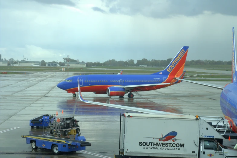 a red and blue plane parked at an airport with people boarding