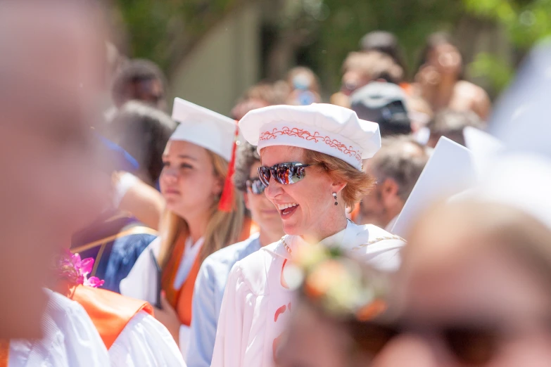 a group of graduates are wearing white robes and hats