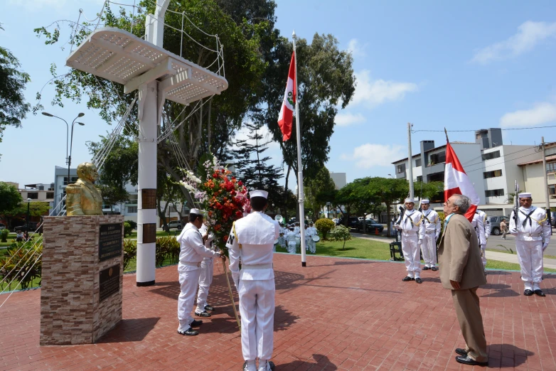 the men are dressed in uniform and standing in front of a memorial