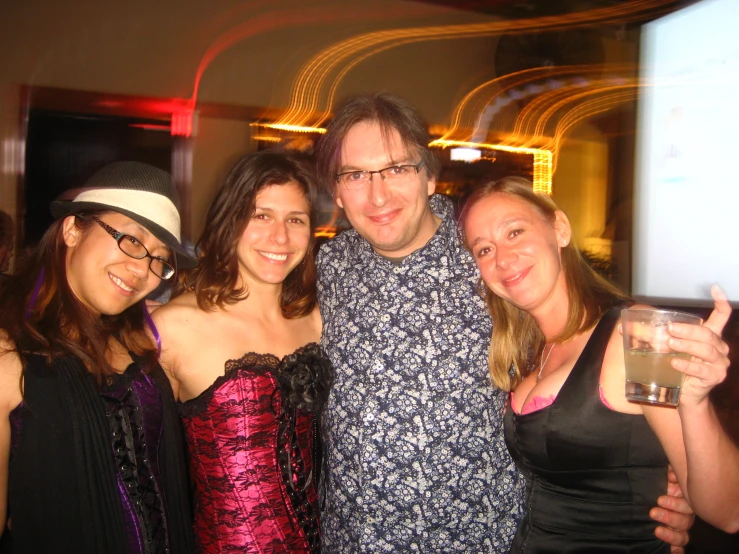 a group of people with one woman holding a drink and the other standing with one man