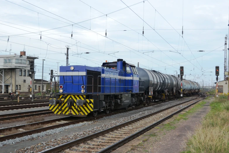 a blue train engine with many carts going down the tracks