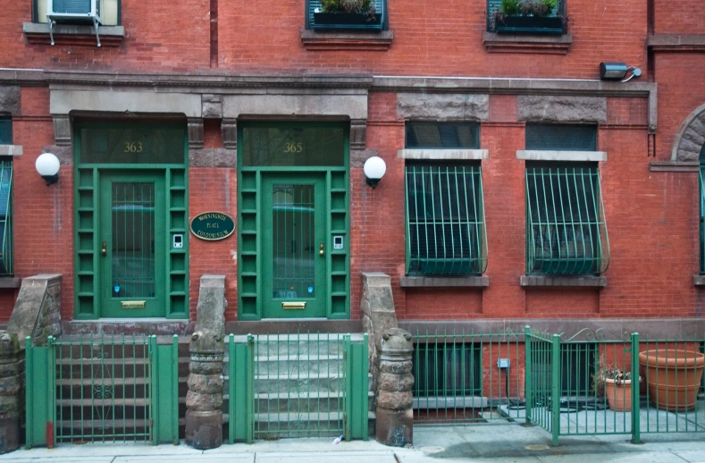 a large building with two green doors and three windows