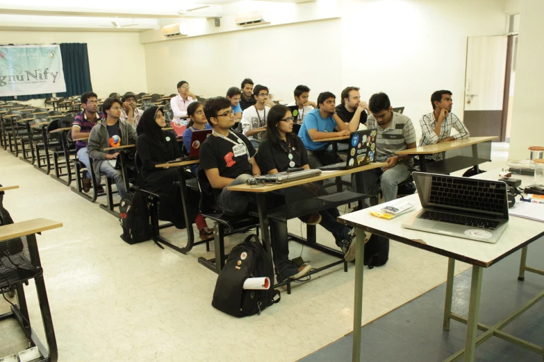 people in a classroom with desks and luggage