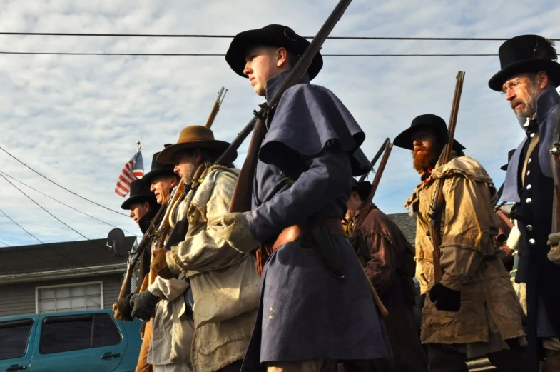 men dressed in uniforms and hats, with guns and poles