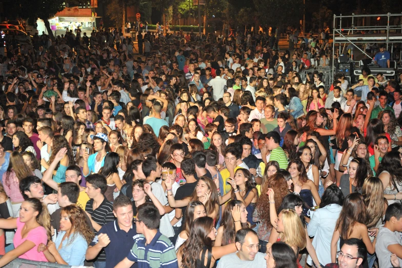 the large group of people are all standing in front of a stage