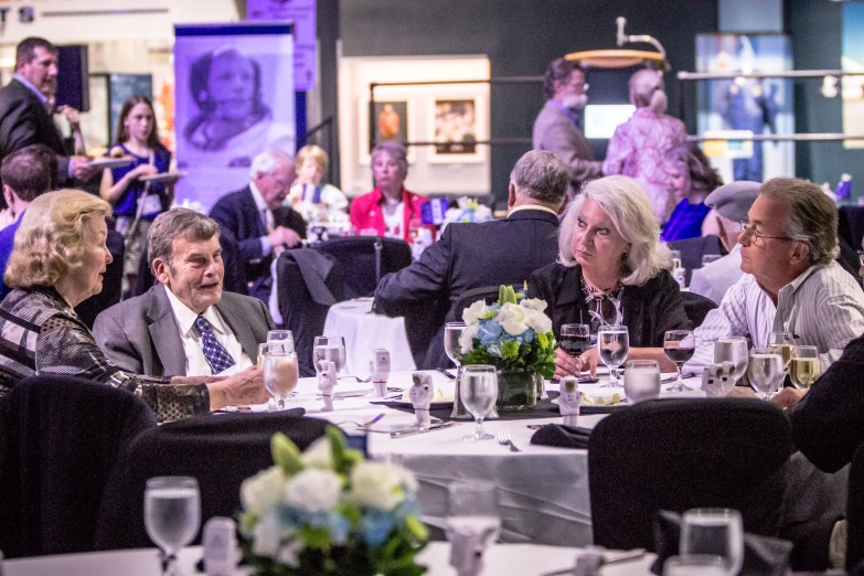 a crowded table with people sitting around them and looking off in the distance