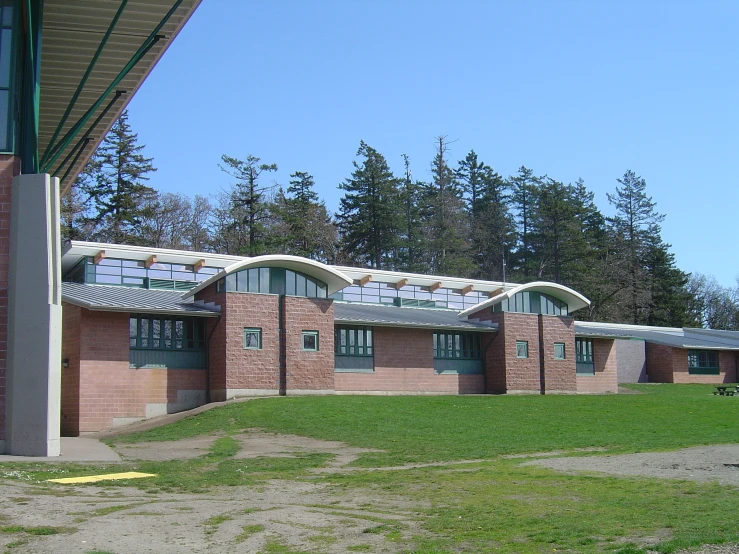 a brick building with glass windows and green grass in front of it