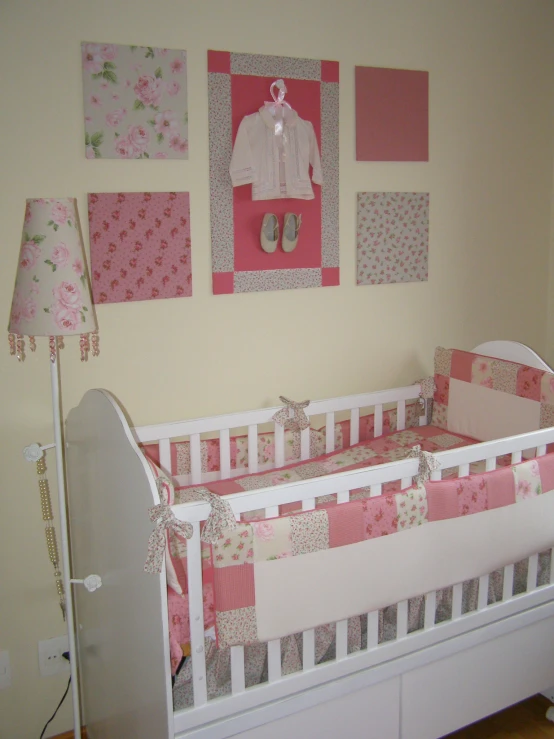 a baby bed next to some wall hangings and pink accents