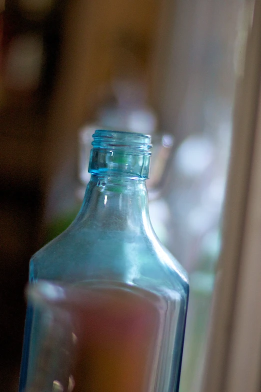 a glass bottle with pink liquid sitting next to a window