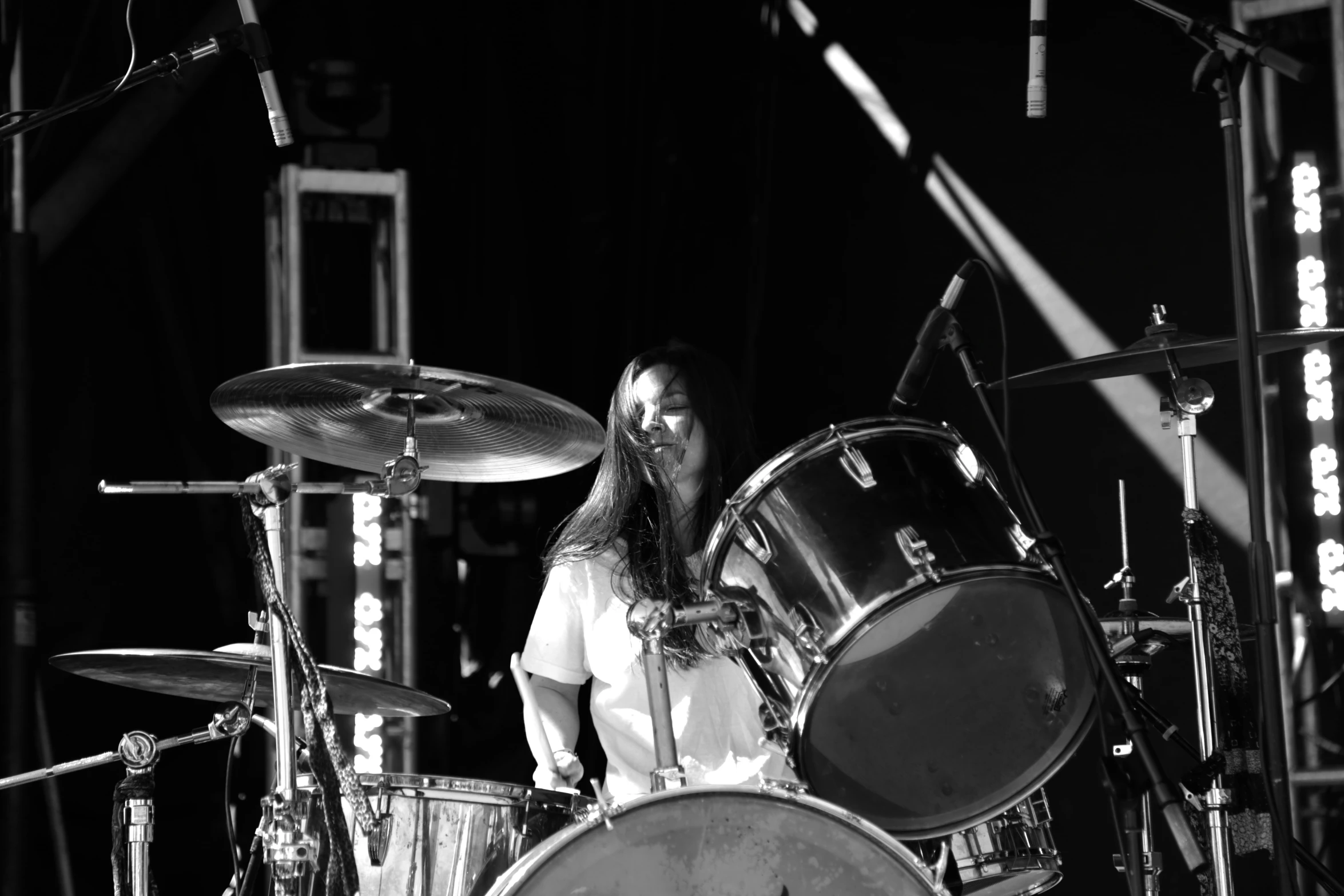 the drummer plays drums on the stage in black and white