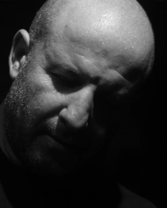 a bald man in the dark with a hair comb