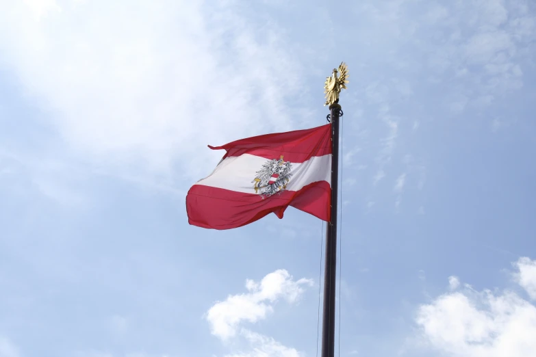 a red and white flag flying in the blue sky