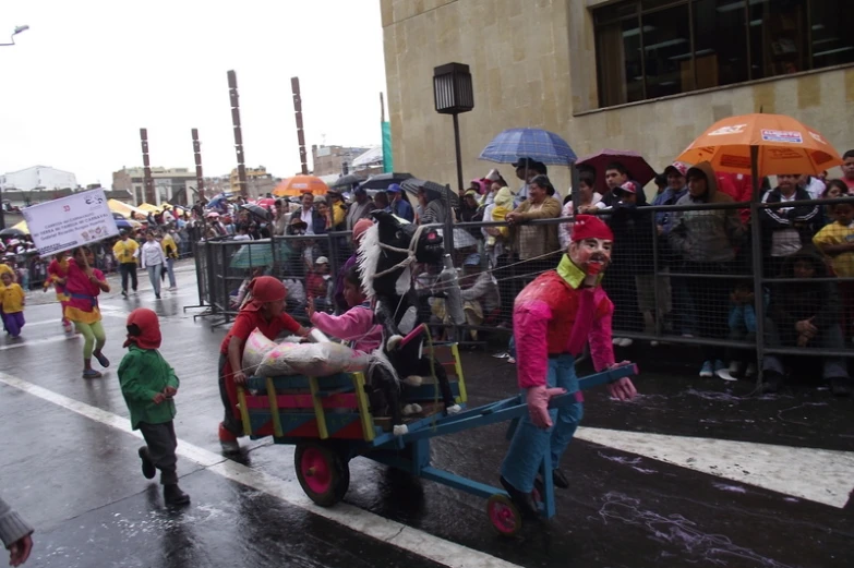 people holding umbrellas, pulling a cart with stuffed animals