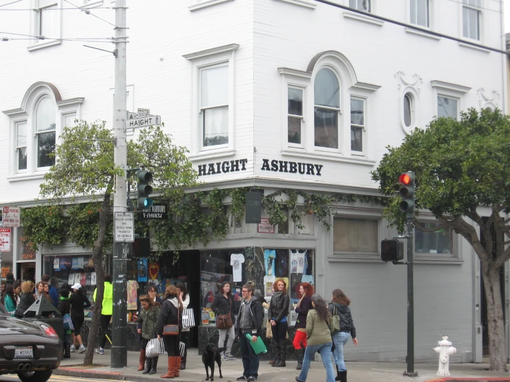 a street corner with people walking by, and two stop lights