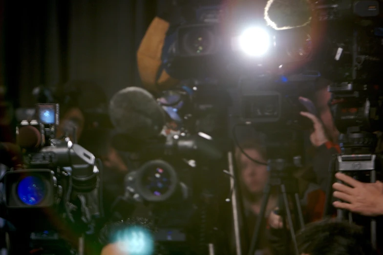 many cameras and lighting equipment in a darkened room