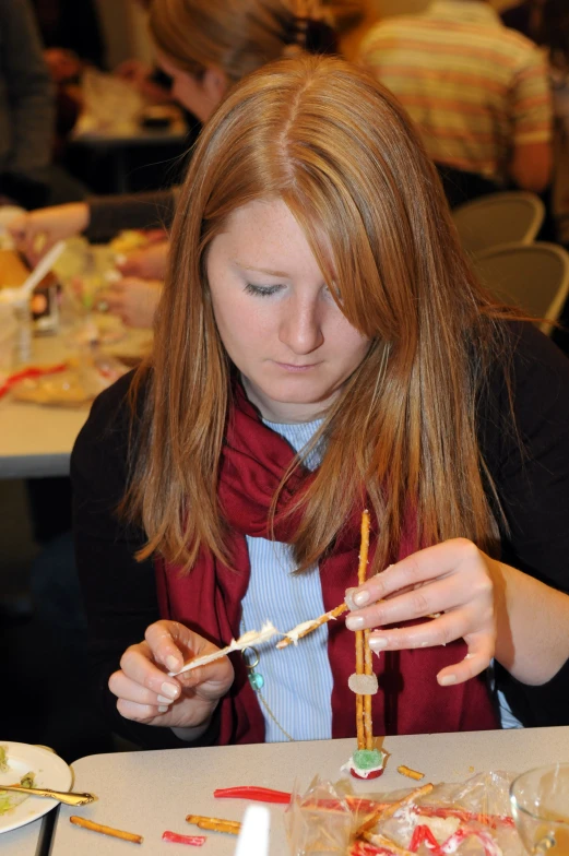 woman using craft sticks on paper making decorations