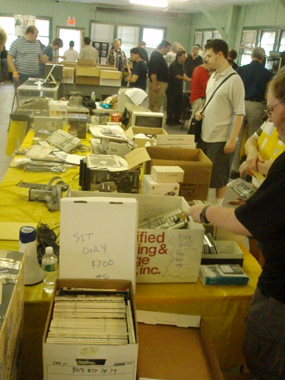 the group of people are gathered around boxes full of items