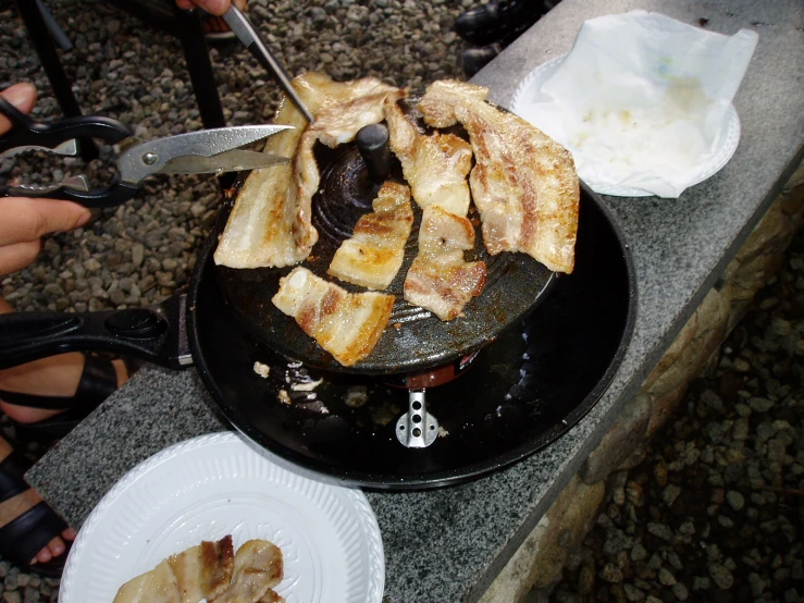 a woman holding tongs slicing up some food