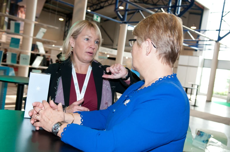 two women are sitting at a table with one woman in blue