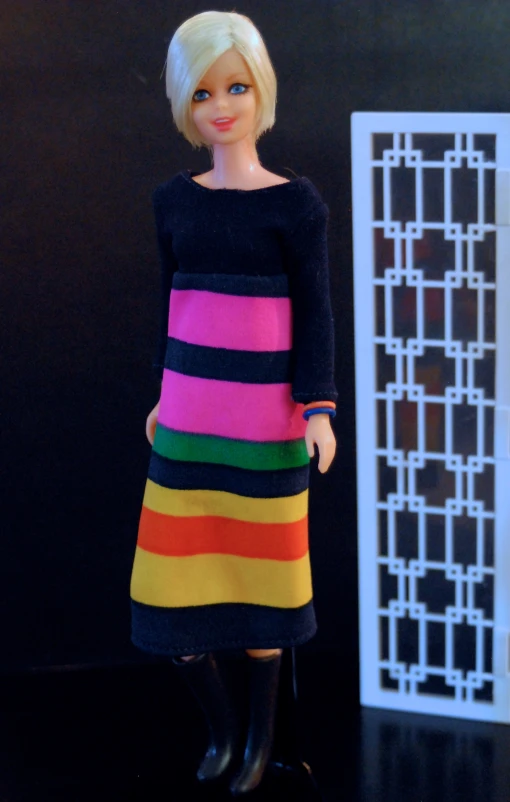 doll with brightly striped dress standing next to a fence